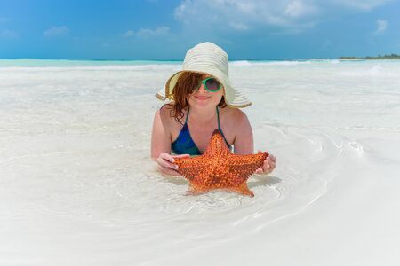 Young woman holding a starfish on a tropical beach in Cayo Largoの写真素材