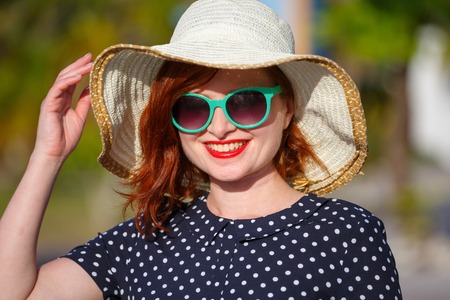 Red-haired girl in a hat and sunglasses on the background of the seaの写真素材