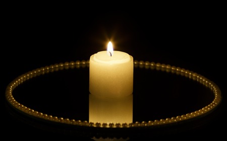 Candle on mirror plate and black backgroundの写真素材