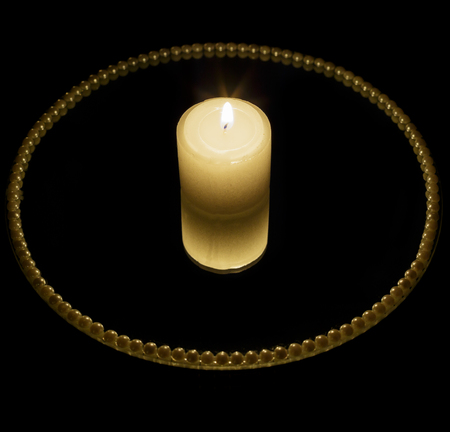 Candle on mirror plate and black backgroundの写真素材