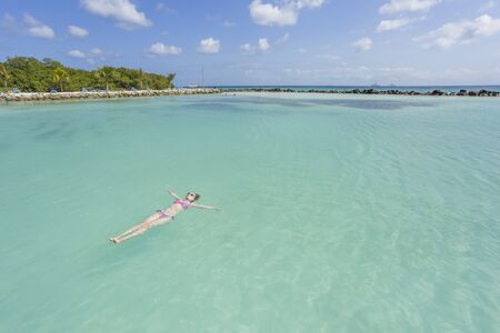 Woman floating and relaxing in turquoise waters at colorful tropical beachの写真素材