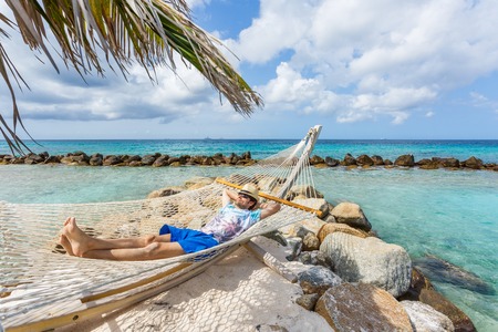 Man in hat in a hammock on caribbean beachの写真素材