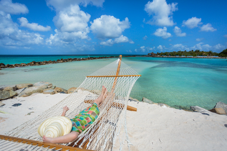Woman in hat in a hammock on caribbean beachの写真素材