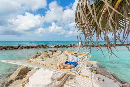 Man in hat in a hammock on caribbean beachの写真素材