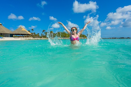 Woman jumping on a back in the beautiful sea. Aruba islandの写真素材