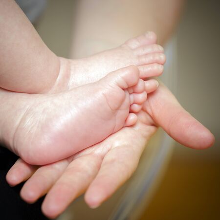 Feet of newborn baby in the hand of motherの写真素材