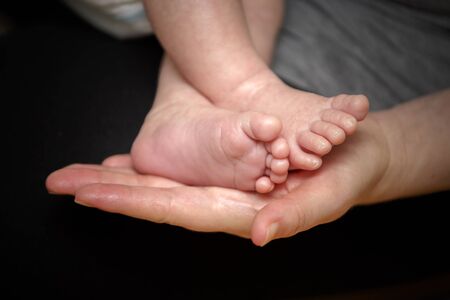 Feet of newborn baby in the hand of motherの写真素材