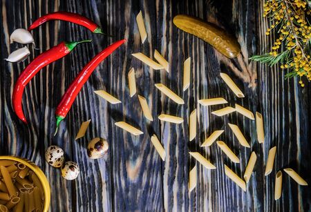 Pasta and other ingredients for cooking on an old wooden table in the morning lightの写真素材