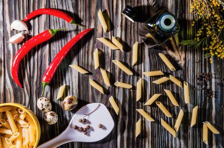 Pasta and other ingredients for cooking on an old wooden table in the morning lightの写真素材
