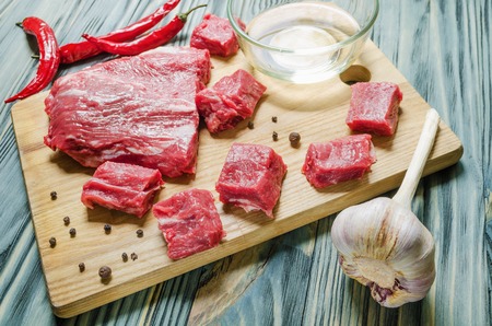 a piece of fresh meat on a cutting board with a knife and pepperの写真素材