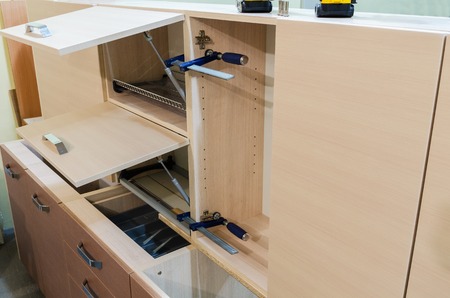 Assembling furniture from chipboard, using a cordless screwdriver, close up.の写真素材