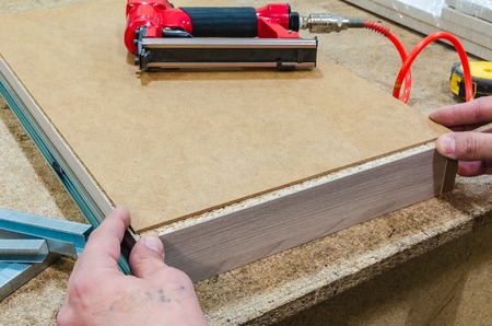Red pneumatic stapler nails the bottom to the drawerの写真素材