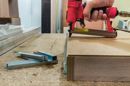 Red pneumatic stapler nails the bottom to the drawerの写真素材