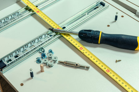 Assembling furniture, installing guides for drawers on furniture panels close-up.