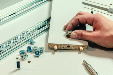 Assembling furniture, installing guides for drawers on furniture panels close-up.