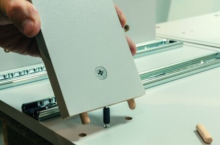 Assembling furniture, installing guides for drawers on furniture panels close-up.の写真素材