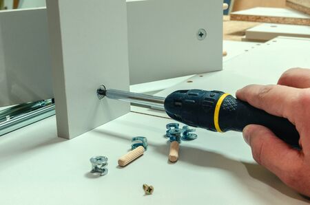 Assembling furniture, installing guides for drawers on furniture panels close-up.の写真素材