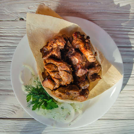 Grilled meat laid out on a plate in pita bread with herbs and fresh onions.の写真素材