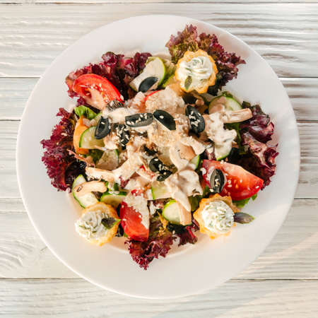 summer vegetable salad on a white dish on a wooden backgroundの写真素材