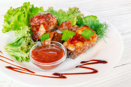 Grilled fried meat on a plate with salad and herbs, shish kebab in tomato sauceの写真素材