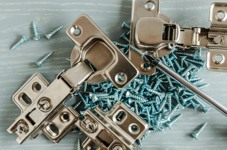 Chrome furniture screws close up on wooden background