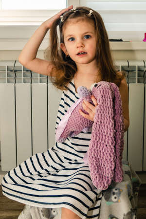 A little girl plays with her toy while she gets her hair done at home.の写真素材