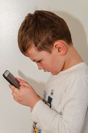 Little boy enthusiastically plays on the smartphone..の写真素材