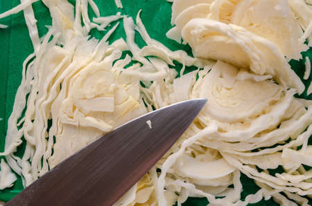 Sliced cabbage on a cutting board with a knife.の写真素材