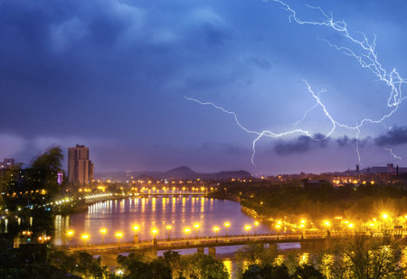 Thunderstorm with lightning over night city sky.