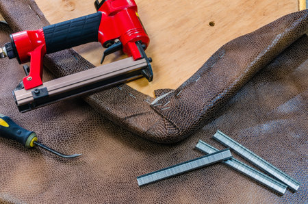 manufacture of upholstered furniture, upholstery of a furniture element with a pneumatic stapler, close-upの写真素材