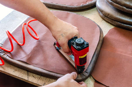 manufacture of upholstered furniture, upholstery of a furniture element with a pneumatic stapler, close-upの写真素材
