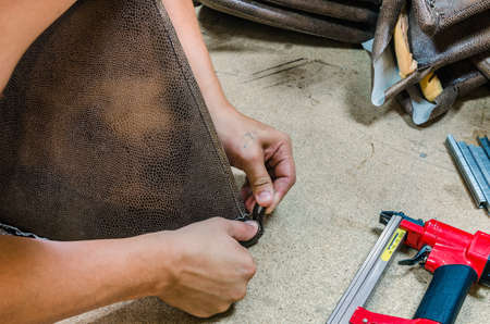 manufacture of upholstered furniture, upholstery of a furniture element with a pneumatic stapler, close-upの写真素材