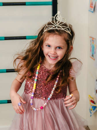 a little girl in a beautiful dress and crown plays and runs around the house.の写真素材