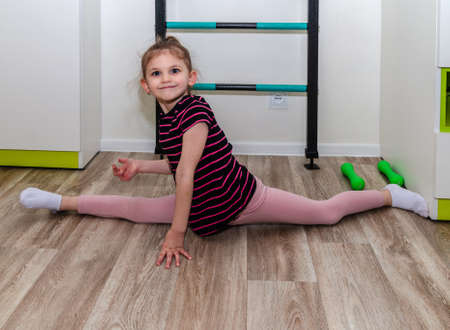 A little girl goes in for sports in her room.の写真素材