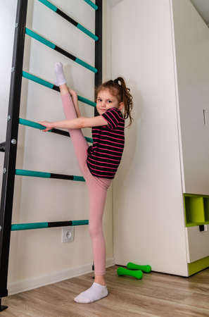A little girl goes in for sports in her room.の写真素材