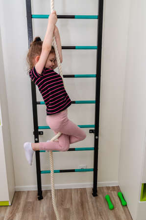 A little girl goes in for sports in her room.の写真素材