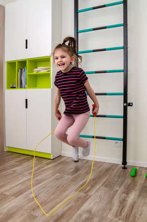 A little girl goes in for sports in her room.の写真素材