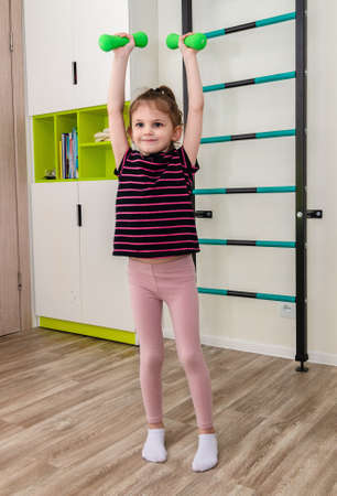 A little girl goes in for sports in her room.の写真素材