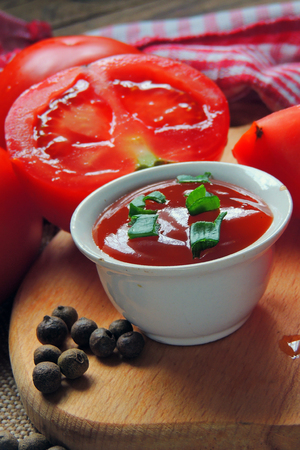 Tomato ketchup sauce with garlic, spices and herbs with cherry tomatoes in a glass bowl on stone table, selective focus.の写真素材