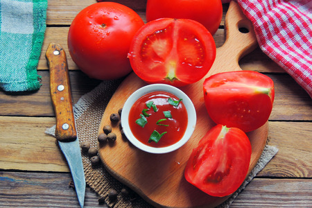 Tomato ketchup sauce with garlic, spices and herbs with cherry tomatoes in a glass bowl on stone table, selective focus.の写真素材
