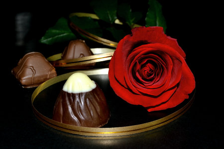 The studio red rose with golden ribbon, chocolate candy on a black background. Valentine's day backgroundの写真素材