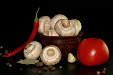Vegetables. Mushrooms on a plate, red hot pepper, tomato garlic and spice on black backgroundの写真素材