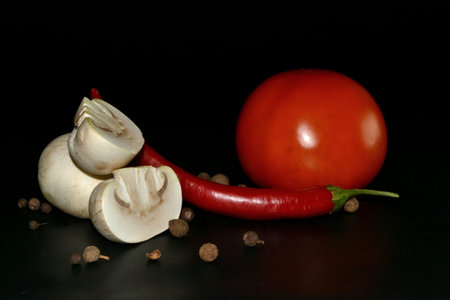cutted mushroom, red hot pepper, tomato and allspice on black backgroundの写真素材