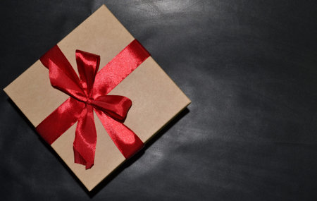 Gift box with a red bow on a dark background. Space for text