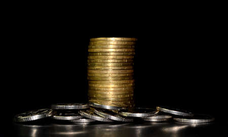 Stack of golden coins and heap of silver coins on black backgroundの写真素材