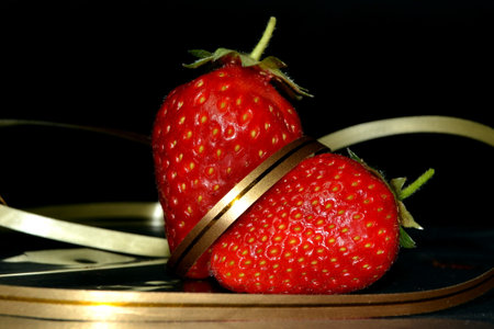 Two fresh red strawberries with golden ribbonの写真素材