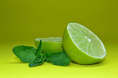 Lime fruit and mint leaves isolated on green background.の写真素材