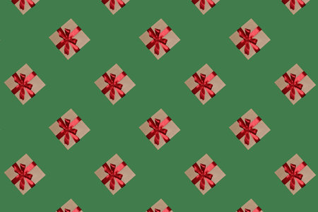 A pattern of gift boxes with a bow made with ribbon isolated on a green backgroundの写真素材