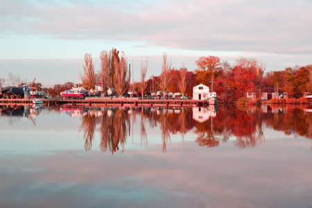 Autumn reflections at the river. Concept photo of the coming of autumn. Beautiful landscape with yellow trees and sky at riverの写真素材