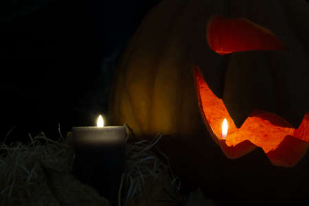 Halloween scary pumpkin with burning candles. Dark backgroundの写真素材